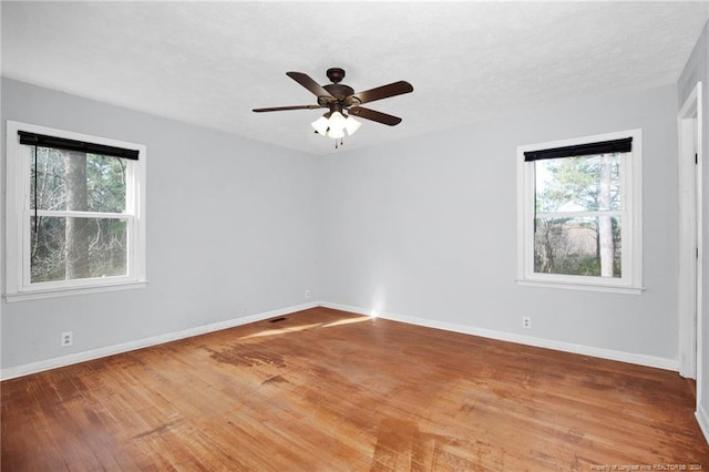 spare room featuring ceiling fan, a healthy amount of sunlight, and wood-type flooring