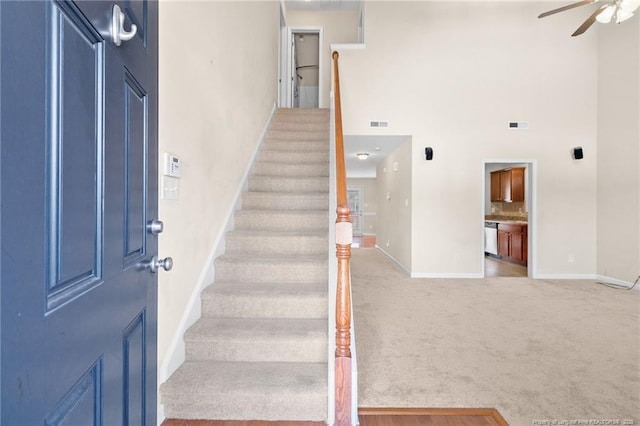 staircase with a ceiling fan, carpet, visible vents, and baseboards