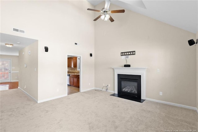 unfurnished living room featuring ceiling fan, light carpet, a fireplace with flush hearth, visible vents, and baseboards