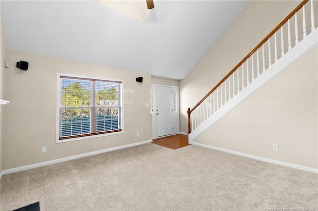 foyer featuring lofted ceiling, light carpet, stairway, and baseboards