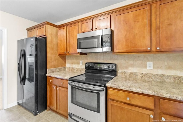 kitchen with appliances with stainless steel finishes, brown cabinetry, backsplash, and light stone counters