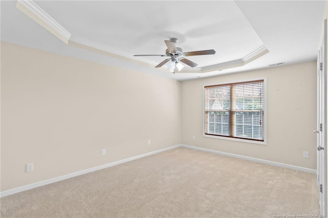 spare room with ceiling fan, light carpet, baseboards, a raised ceiling, and crown molding