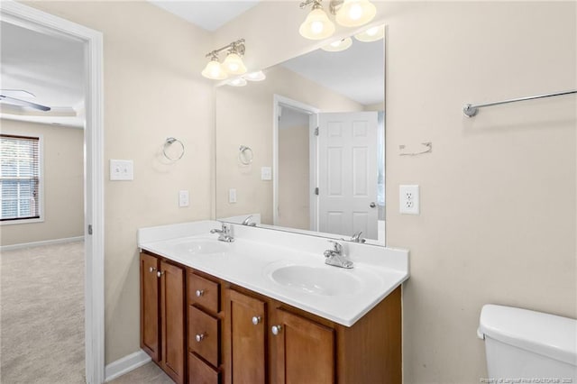 full bath with ceiling fan, double vanity, a sink, and toilet