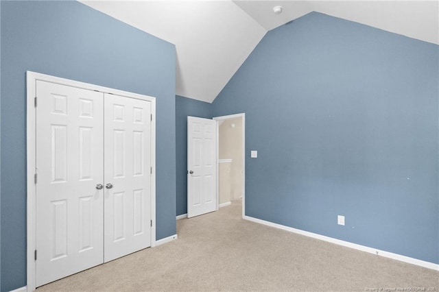 unfurnished bedroom with a closet, light carpet, vaulted ceiling, and baseboards