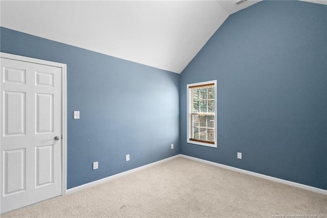 carpeted empty room with lofted ceiling and baseboards