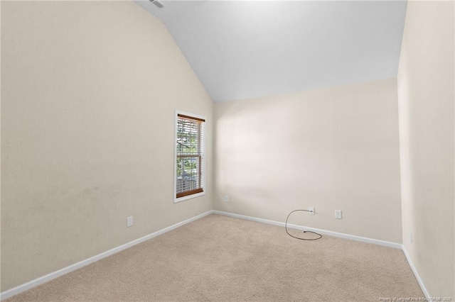 spare room featuring light carpet, high vaulted ceiling, and baseboards