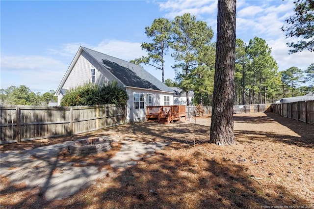 rear view of property featuring a fenced backyard, a fire pit, and a wooden deck