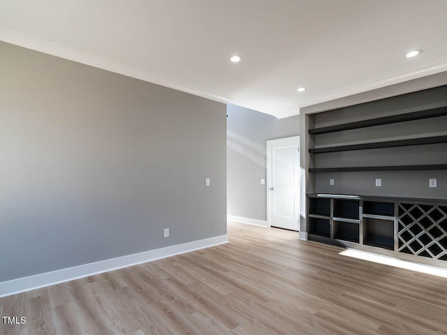 unfurnished living room with built in features, light wood-type flooring, and crown molding