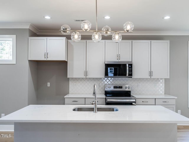 kitchen featuring light stone counters, sink, stainless steel appliances, and decorative light fixtures