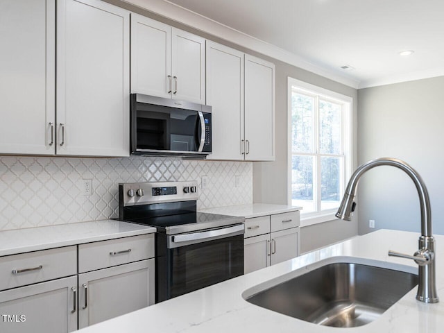 kitchen featuring sink, light stone countertops, stainless steel appliances, and tasteful backsplash