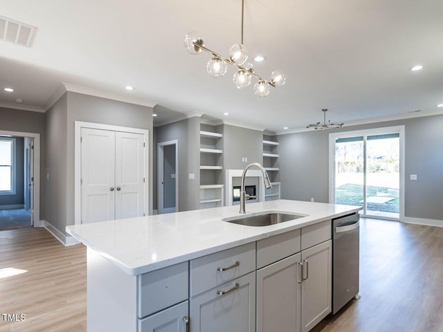 kitchen featuring sink, stainless steel dishwasher, light wood-type flooring, an island with sink, and light stone counters