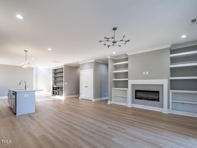 unfurnished living room with sink, crown molding, light hardwood / wood-style flooring, built in shelves, and a notable chandelier