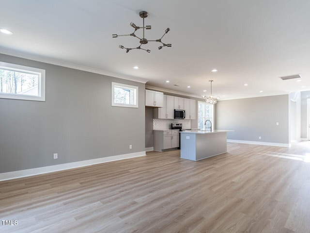 kitchen with a kitchen island with sink, decorative light fixtures, tasteful backsplash, a notable chandelier, and white cabinetry