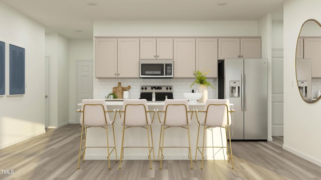 kitchen with decorative backsplash, a breakfast bar, stainless steel appliances, a kitchen island with sink, and light hardwood / wood-style flooring