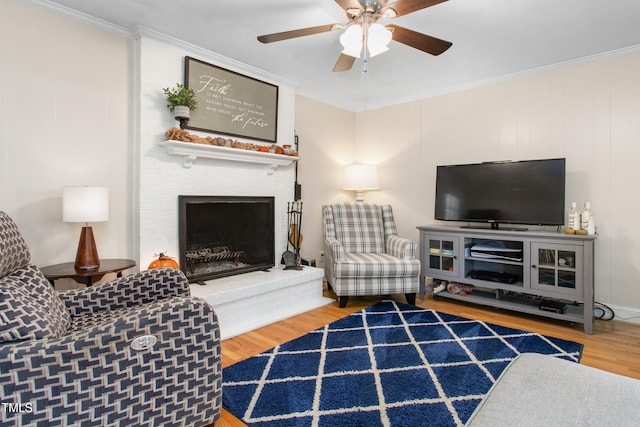 living room with hardwood / wood-style floors, ornamental molding, and a brick fireplace