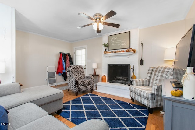 living room with a fireplace, hardwood / wood-style flooring, ceiling fan, and ornamental molding