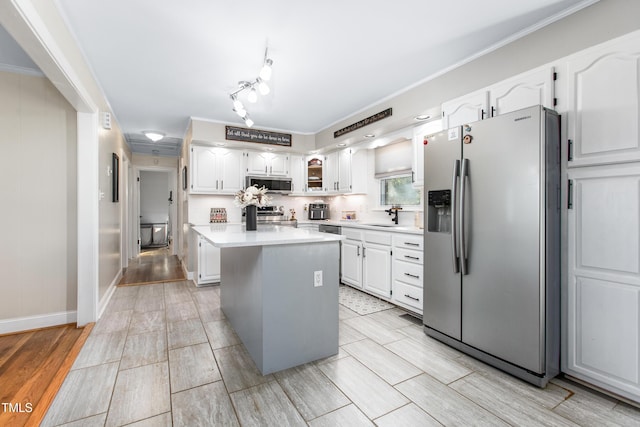 kitchen with a center island, stainless steel appliances, white cabinetry, and crown molding