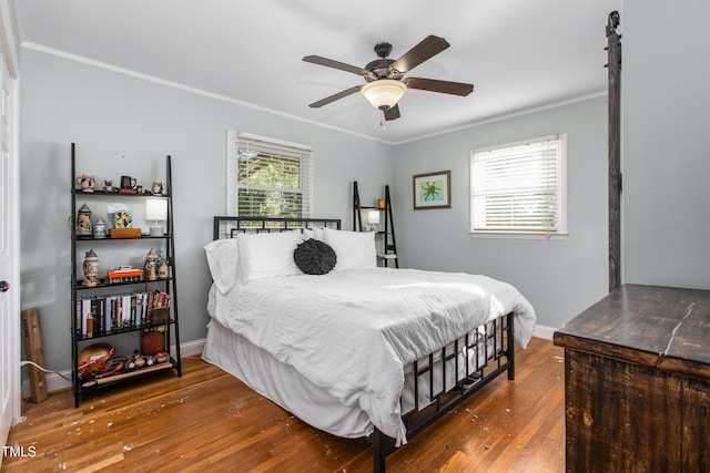 bedroom featuring multiple windows, hardwood / wood-style flooring, ceiling fan, and ornamental molding