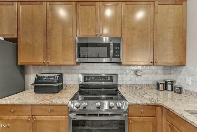 kitchen with decorative backsplash, appliances with stainless steel finishes, and light stone counters