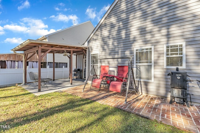 rear view of house with ceiling fan, a yard, and a patio