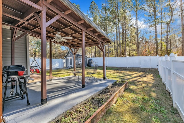 view of yard with ceiling fan, a shed, and a patio