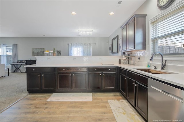 kitchen with stainless steel dishwasher, a wealth of natural light, sink, and light carpet