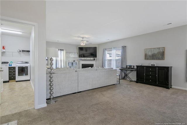 living room featuring ceiling fan, washer and dryer, and light colored carpet