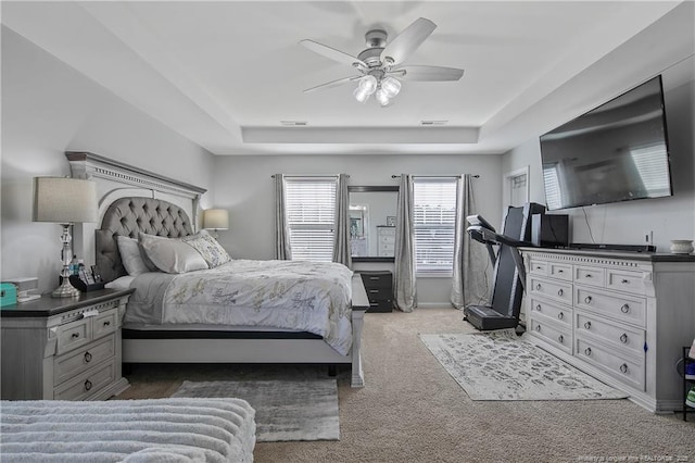 carpeted bedroom featuring ceiling fan and a tray ceiling