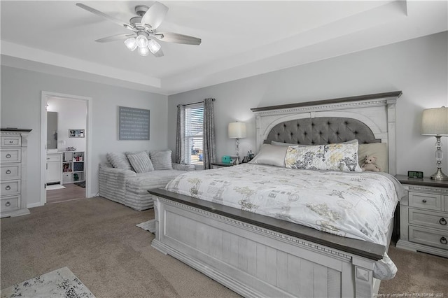 carpeted bedroom featuring ceiling fan and a tray ceiling