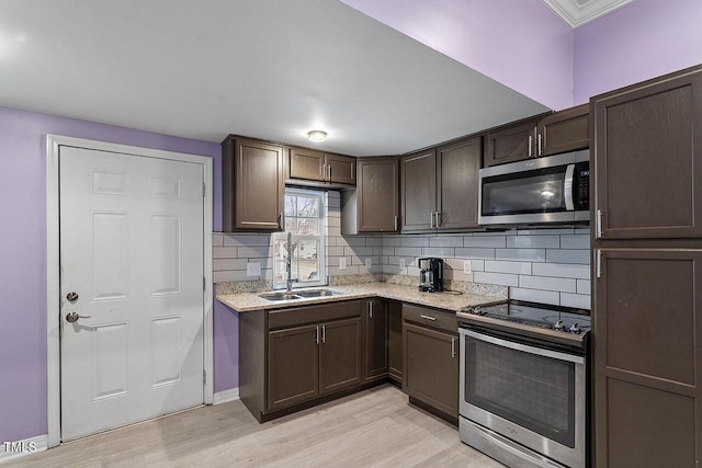 kitchen featuring sink, stainless steel appliances, dark brown cabinets, and light hardwood / wood-style flooring