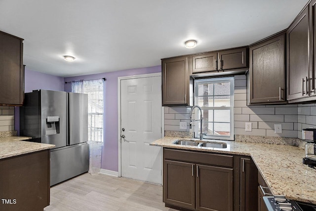 kitchen with backsplash, dark brown cabinets, sink, and stainless steel refrigerator with ice dispenser