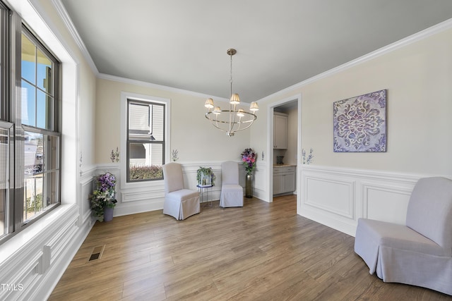 living area with a notable chandelier, crown molding, and light hardwood / wood-style flooring