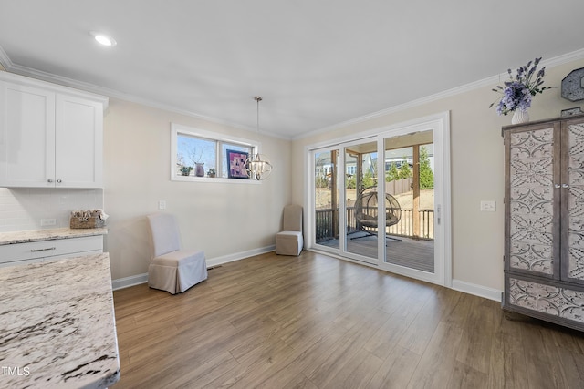 unfurnished room featuring an inviting chandelier, crown molding, and light hardwood / wood-style flooring