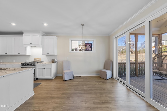 kitchen featuring high end range, light stone countertops, backsplash, a wealth of natural light, and white cabinets