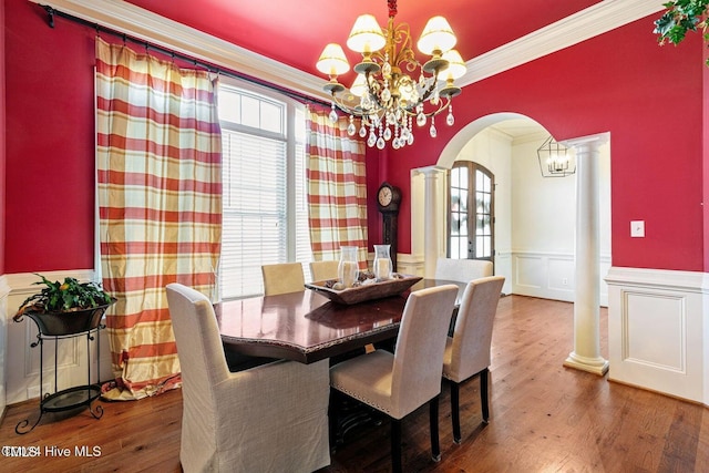 dining space featuring decorative columns, a wealth of natural light, wood-type flooring, and a notable chandelier