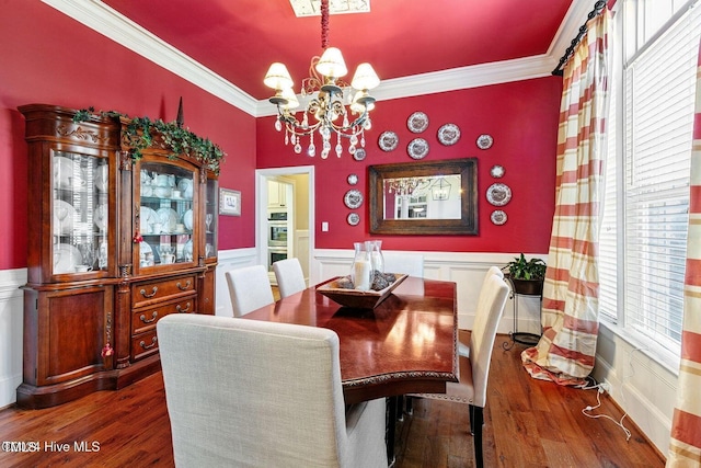 dining space with crown molding, dark wood-type flooring, and an inviting chandelier