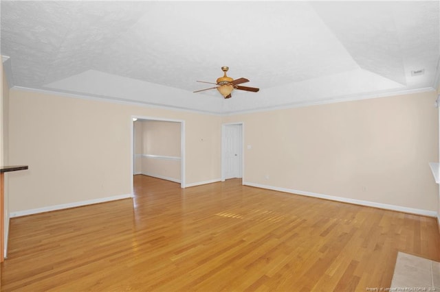 unfurnished room featuring light hardwood / wood-style floors, a raised ceiling, and ornamental molding