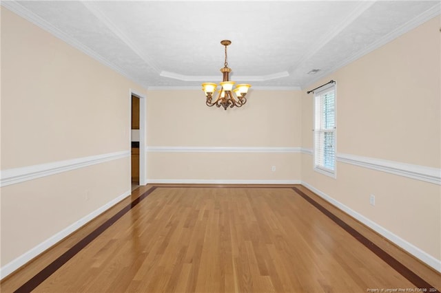 unfurnished dining area with a raised ceiling, wood-type flooring, ornamental molding, and an inviting chandelier