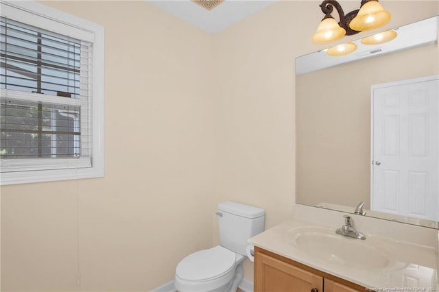 bathroom with vanity, toilet, and a notable chandelier