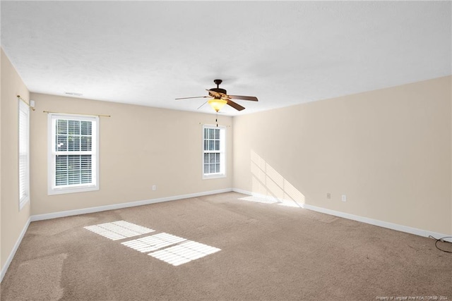 carpeted spare room featuring a wealth of natural light and ceiling fan