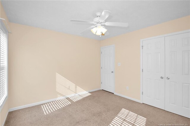 unfurnished bedroom featuring a closet, ceiling fan, and light colored carpet