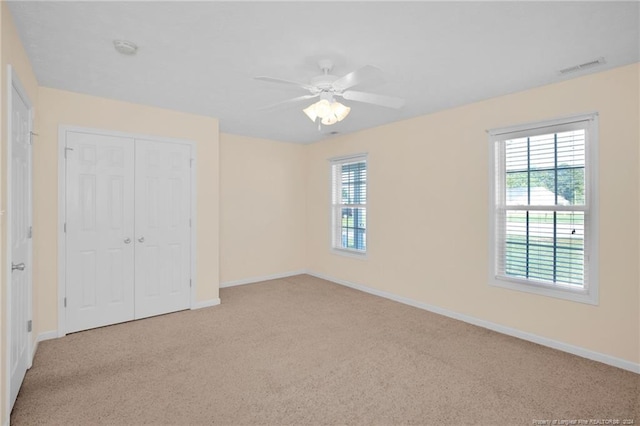 unfurnished bedroom with ceiling fan, light colored carpet, and a closet