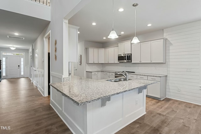 kitchen with hardwood / wood-style flooring, light stone countertops, white cabinetry, and sink