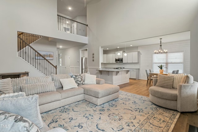 living room featuring a notable chandelier, light hardwood / wood-style floors, and a high ceiling