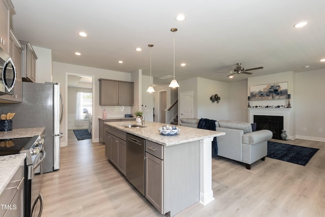 kitchen featuring pendant lighting, a center island with sink, sink, ceiling fan, and appliances with stainless steel finishes