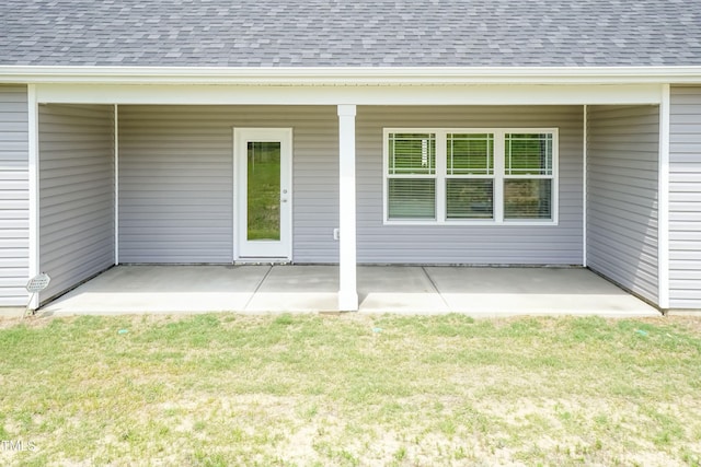 entrance to property featuring a lawn and a patio