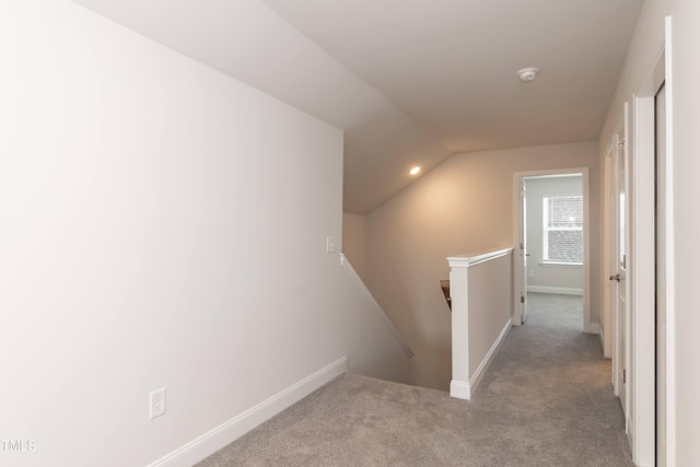 corridor featuring light colored carpet and vaulted ceiling