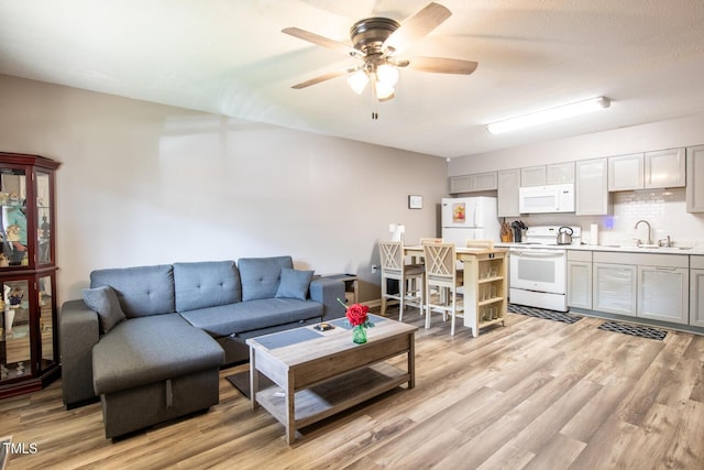 living room featuring ceiling fan, light hardwood / wood-style floors, and sink