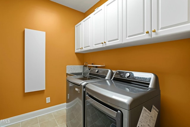 clothes washing area featuring washer and dryer, cabinets, and light tile patterned floors