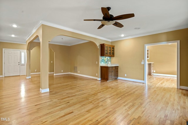 unfurnished living room featuring light wood-type flooring, ceiling fan, and ornamental molding